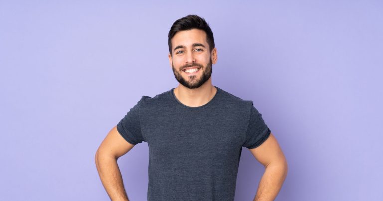 Caucasian handsome man posing with arms at hip and smiling